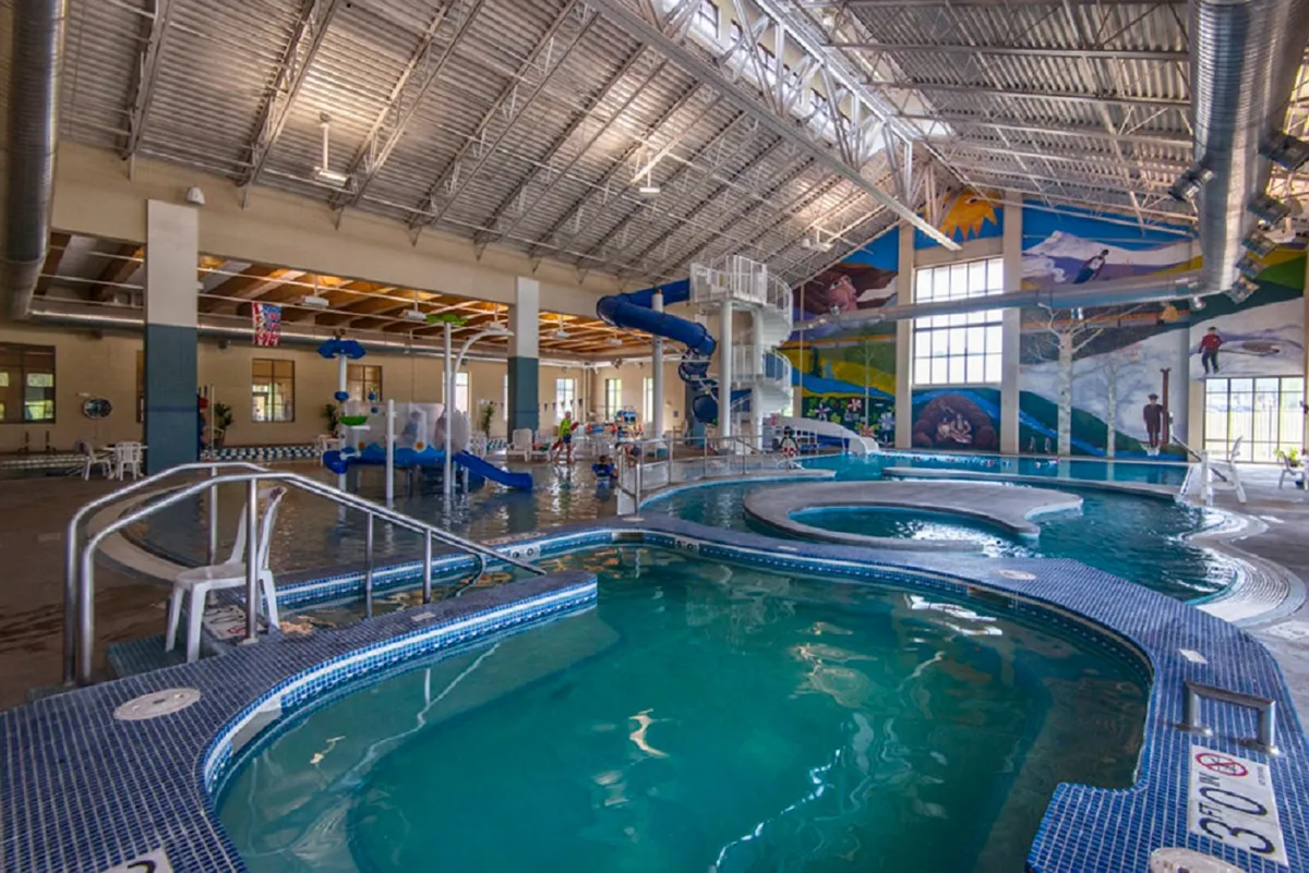 Inside, a vibrant swimming pool area bursts with color, featuring water slides, children playing, and festive murals. The space is filled with natural light and excitement, making it ideal for relaxation and recreation after work.